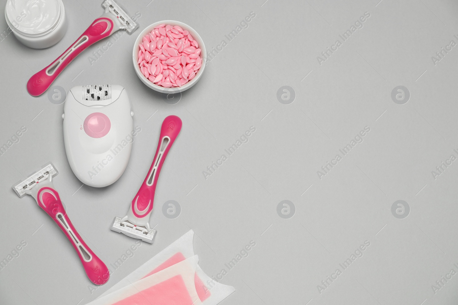 Photo of Modern epilator and other hair removal products on light grey background. Space for text