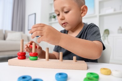 Motor skills development. Little boy playing with stacking and counting game at table indoors, closeup