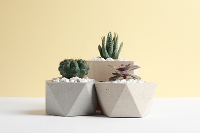 Photo of Beautiful succulent plants in stylish flowerpots on table against yellow background. Home decor