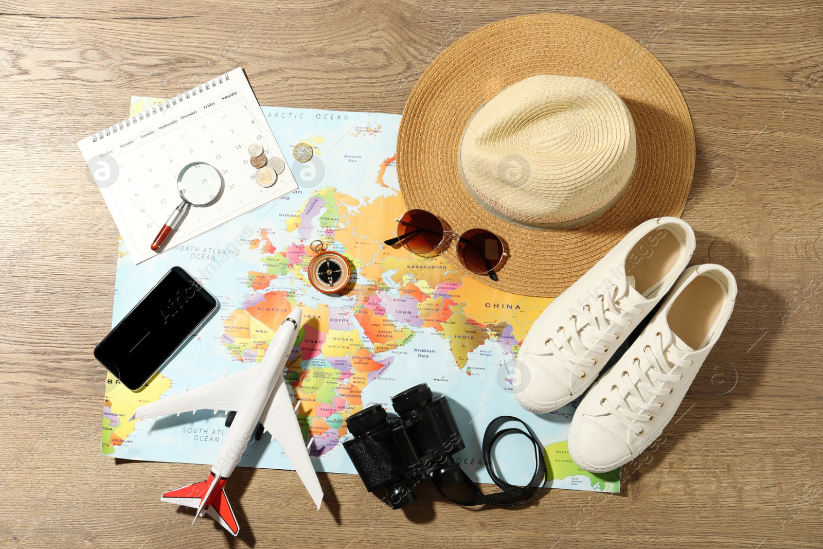 Photo of World map and items on wooden background, flat lay. Travel during summer vacation