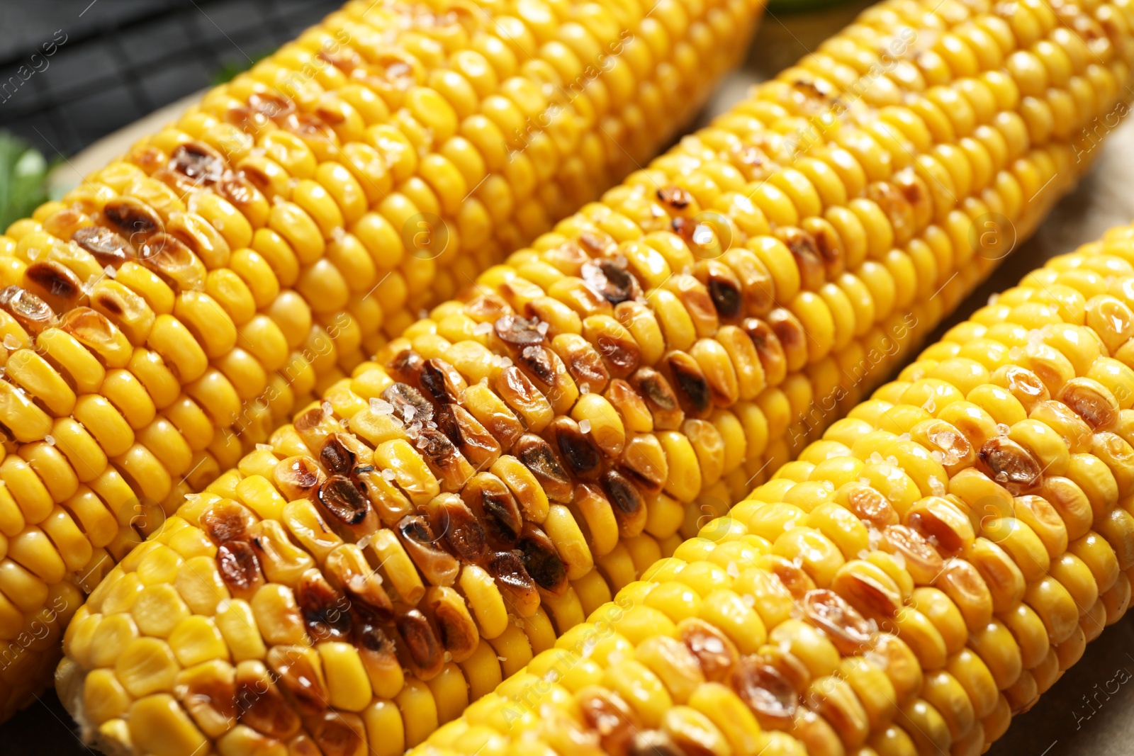 Photo of Tasty grilled corn with salt, closeup view