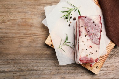 Photo of Tasty salt pork with rosemary and spices on wooden table, top view. Space for text