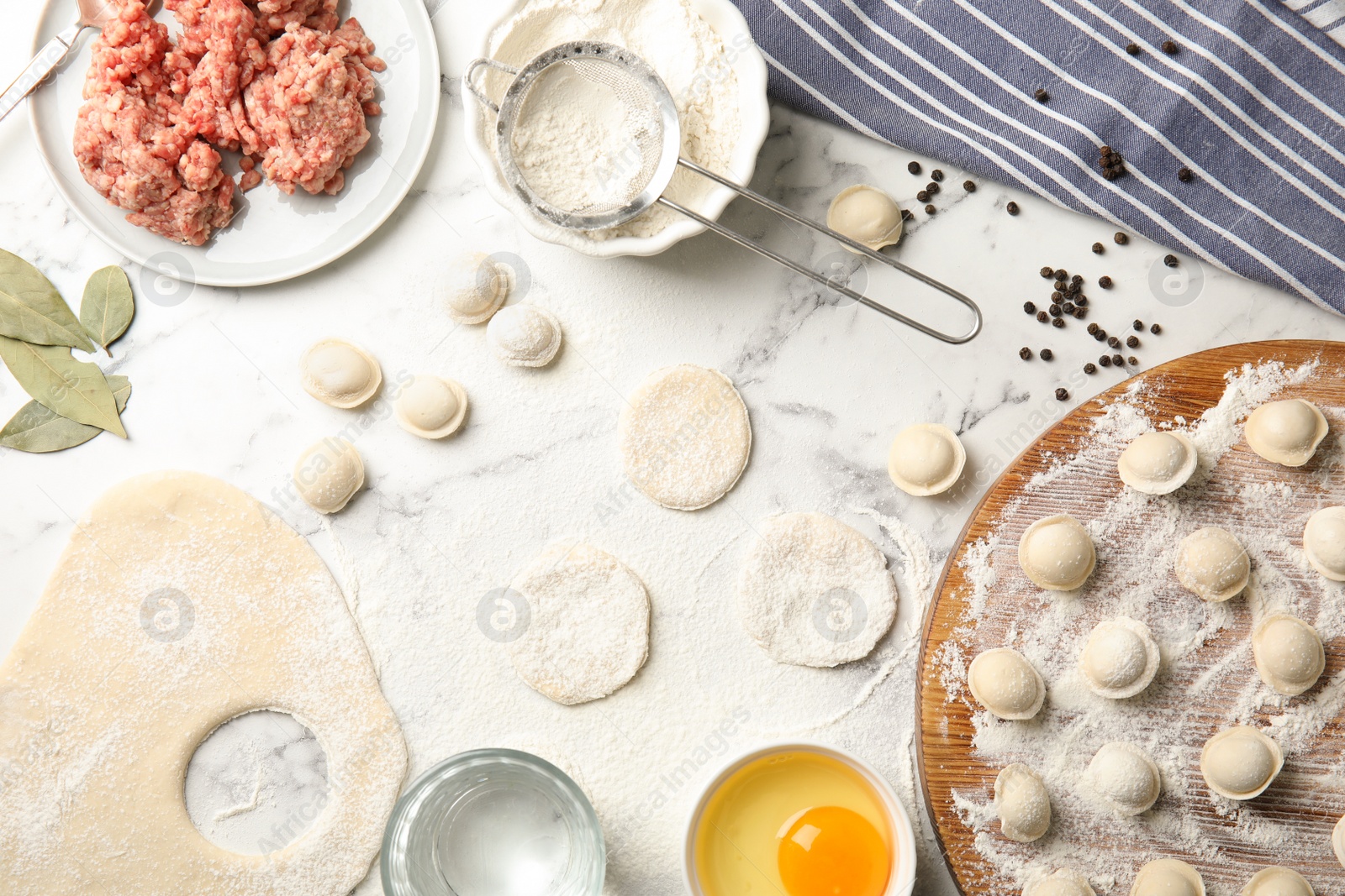 Photo of Flat lay composition with raw dumplings and ingredients on marble background. Process of cooking