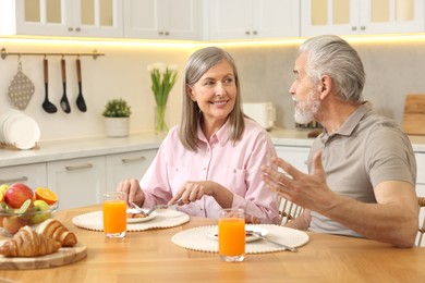 Happy senior couple having breakfast at home