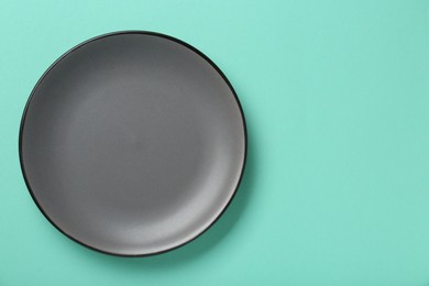 Empty grey ceramic plate on turquoise background, top view. Space for text