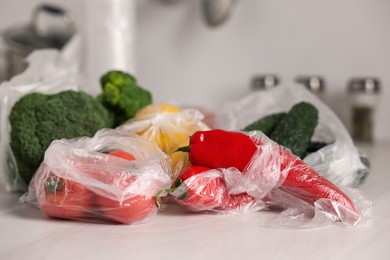 Photo of Plastic bags and fresh products on white table