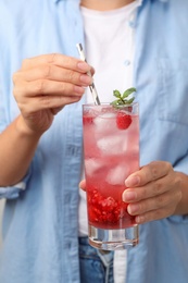 Woman holding glass of raspberry refreshing drink with straw, closeup