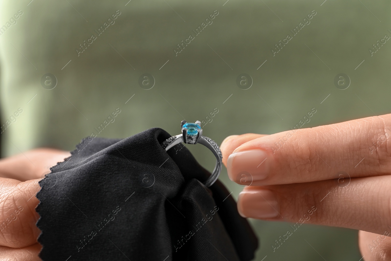 Photo of Jeweler cleaning topaz ring with microfiber cloth, closeup