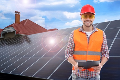 Engineer near house with installed solar panels. Alternative energy source