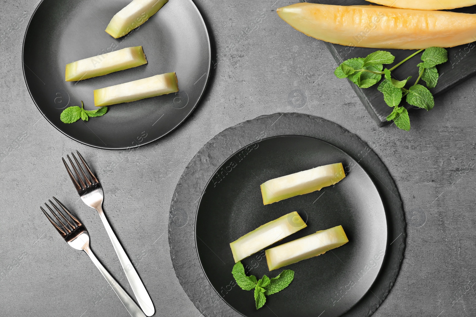 Photo of Slices of fresh ripe melon on gray background, top view