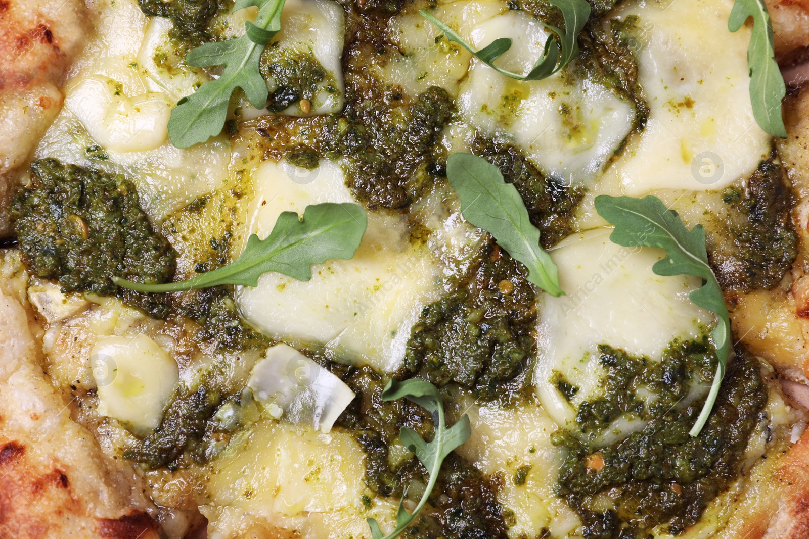 Photo of Delicious pizza with pesto, cheese and arugula as background, top view