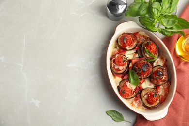 Photo of Baked eggplant with tomatoes, cheese and basil in dishware on light marble table, flat lay. Space for text