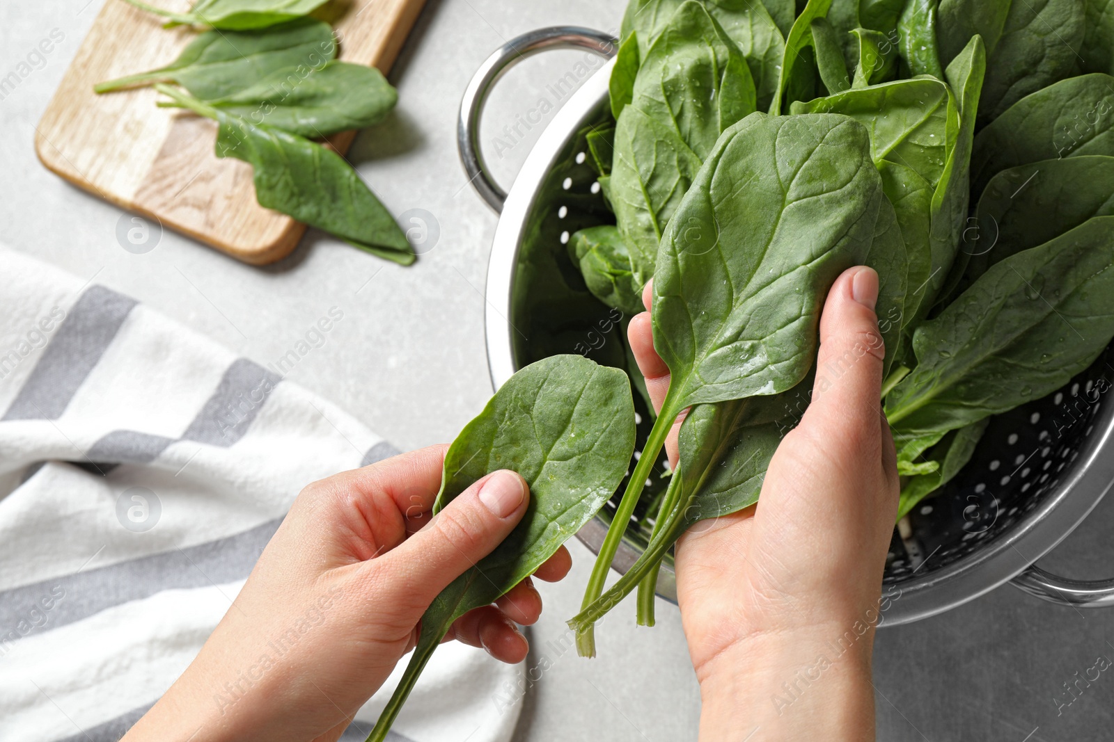 Photo of Woman with fresh green healthy spinach on grey table, closeup view