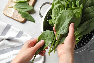 Photo of Woman with fresh green healthy spinach on grey table, closeup view