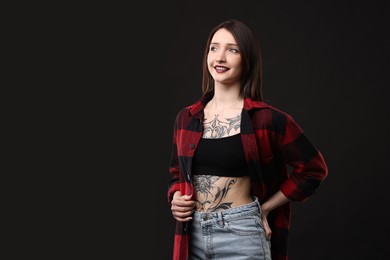 Photo of Portrait of smiling tattooed woman on black background. Space for text