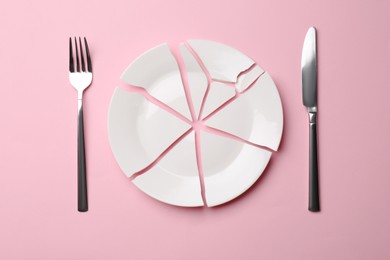 Photo of Pieces of broken ceramic plate and cutlery on pink background, flat lay