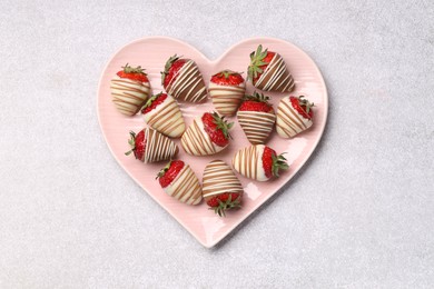 Photo of Heart shaped plate with delicious chocolate covered strawberries on light table, top view