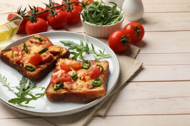 Photo of Tasty pizza toasts and ingredients on light wooden table