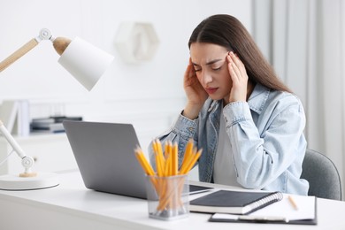 Woman suffering from headache at workplace in office