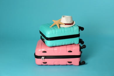 Stylish suitcases with hat and sea star on color background