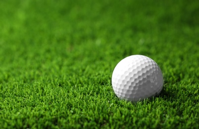 Golf ball on artificial grass, space for text