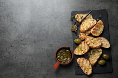 Photo of Tasty bruschettas with oil, thyme and olives on grey table, flat lay. Space for text