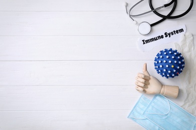 Paper piece with phrase Immune System, mannequin hand and medical items on white wooden table, flat lay. Space for text