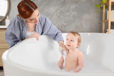 Photo of Mother washing her little baby in tub at home