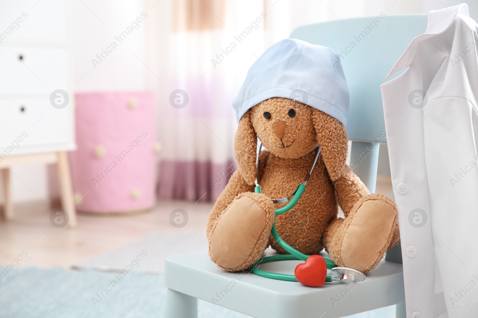 Photo of Composition with toy bunny, stethoscope and heart on chair indoors, space for text. Children's doctor