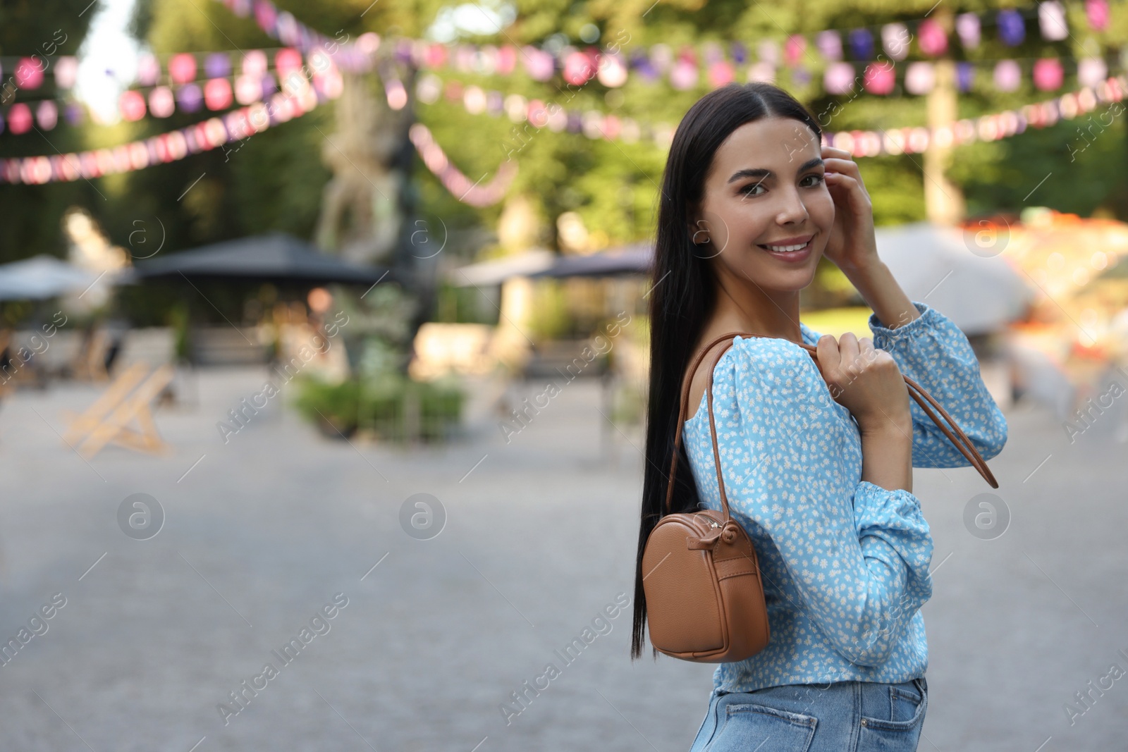 Photo of Young woman with stylish bag outdoors, space for text