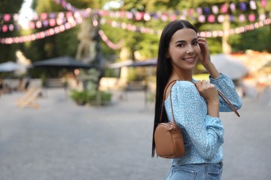 Photo of Young woman with stylish bag outdoors, space for text