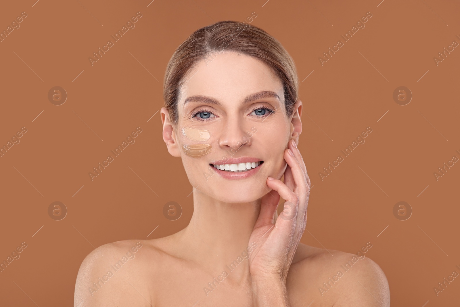 Photo of Woman with swatches of foundation on face against brown background