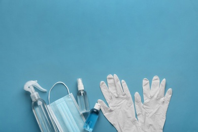 Photo of Medical gloves, mask and hand sanitizers on blue background, flat lay. Space for text