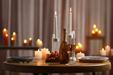 Photo of Festive table setting with burning candles indoors