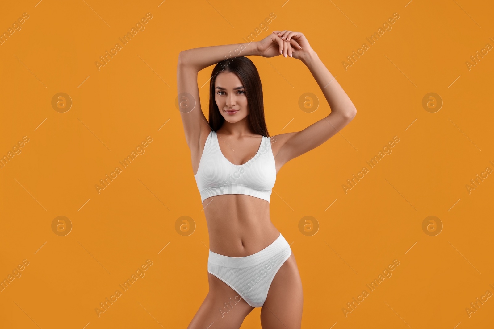 Photo of Young woman in stylish white bikini on orange background