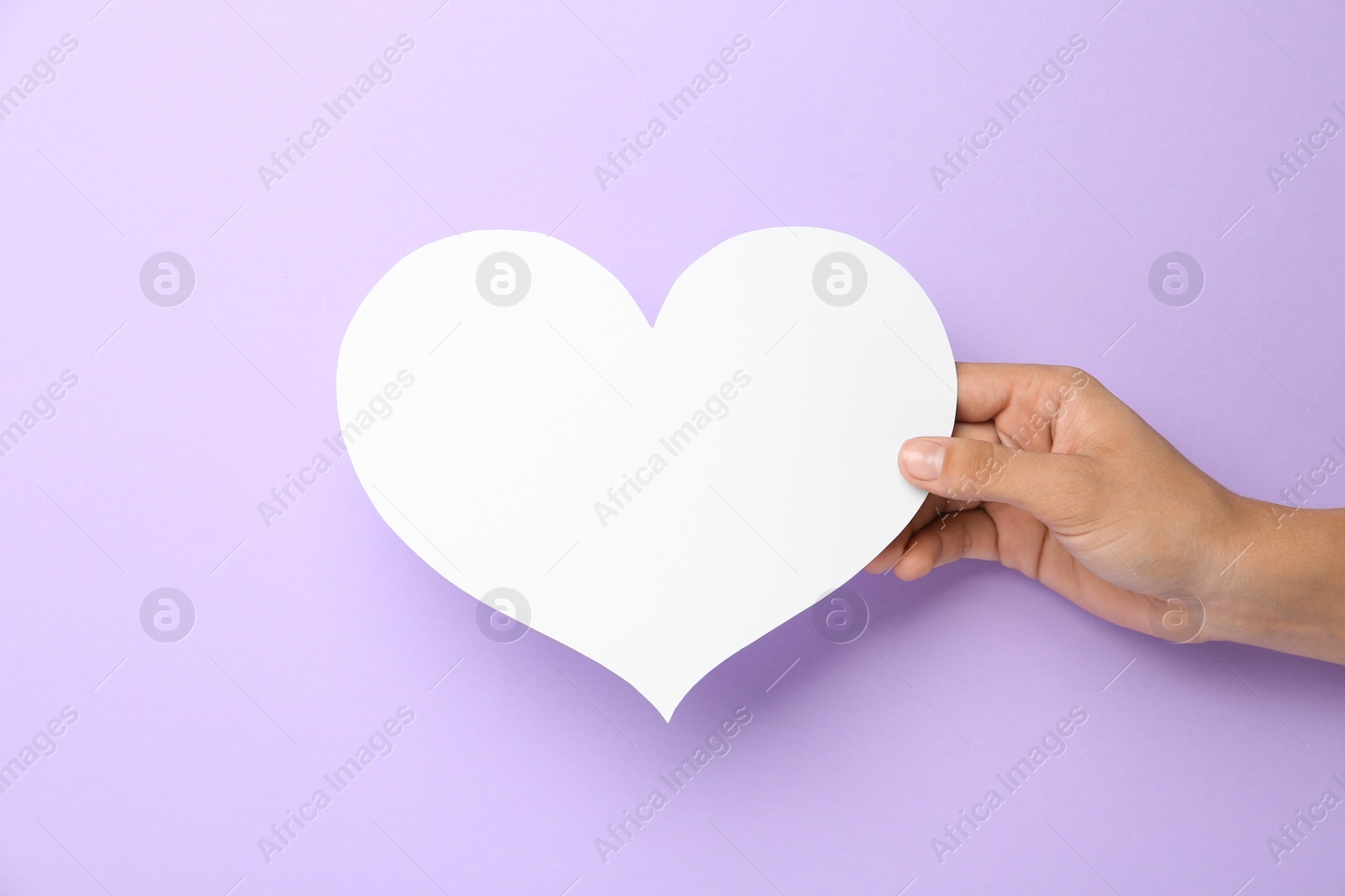 Photo of Woman holding blank paper heart on violet background, closeup. Space for text