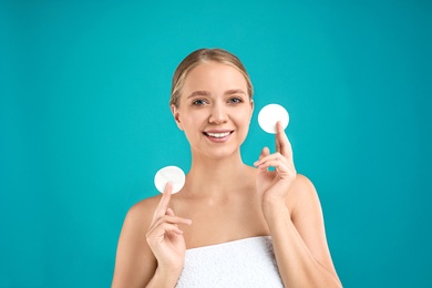 Photo of Beautiful young woman with cotton pads on turquoise background