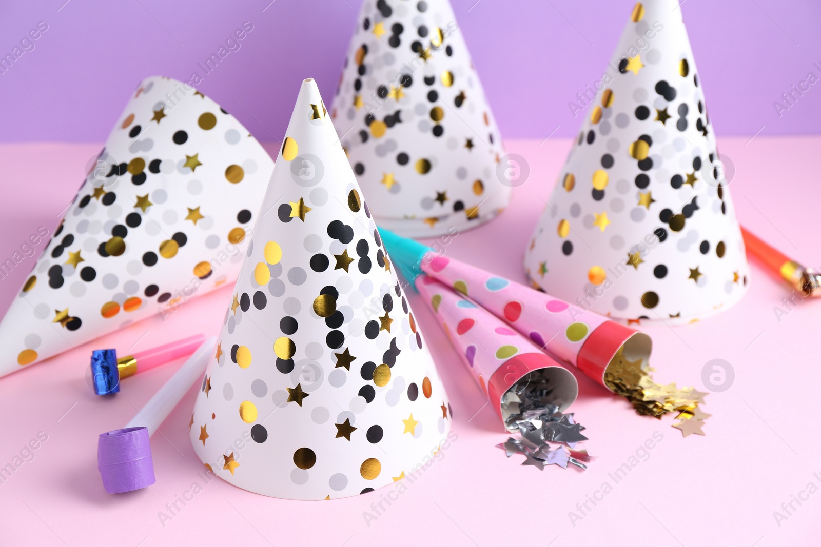 Photo of Party hats, confetti and blowers on color background