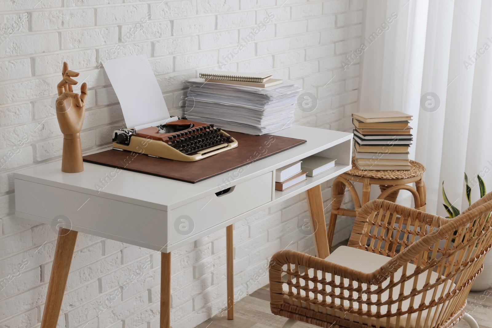 Photo of Comfortable writer's workplace interior with typewriter on desk near white brick wall