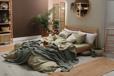 Photo of Stylish interior with large comfortable bed and potted plants