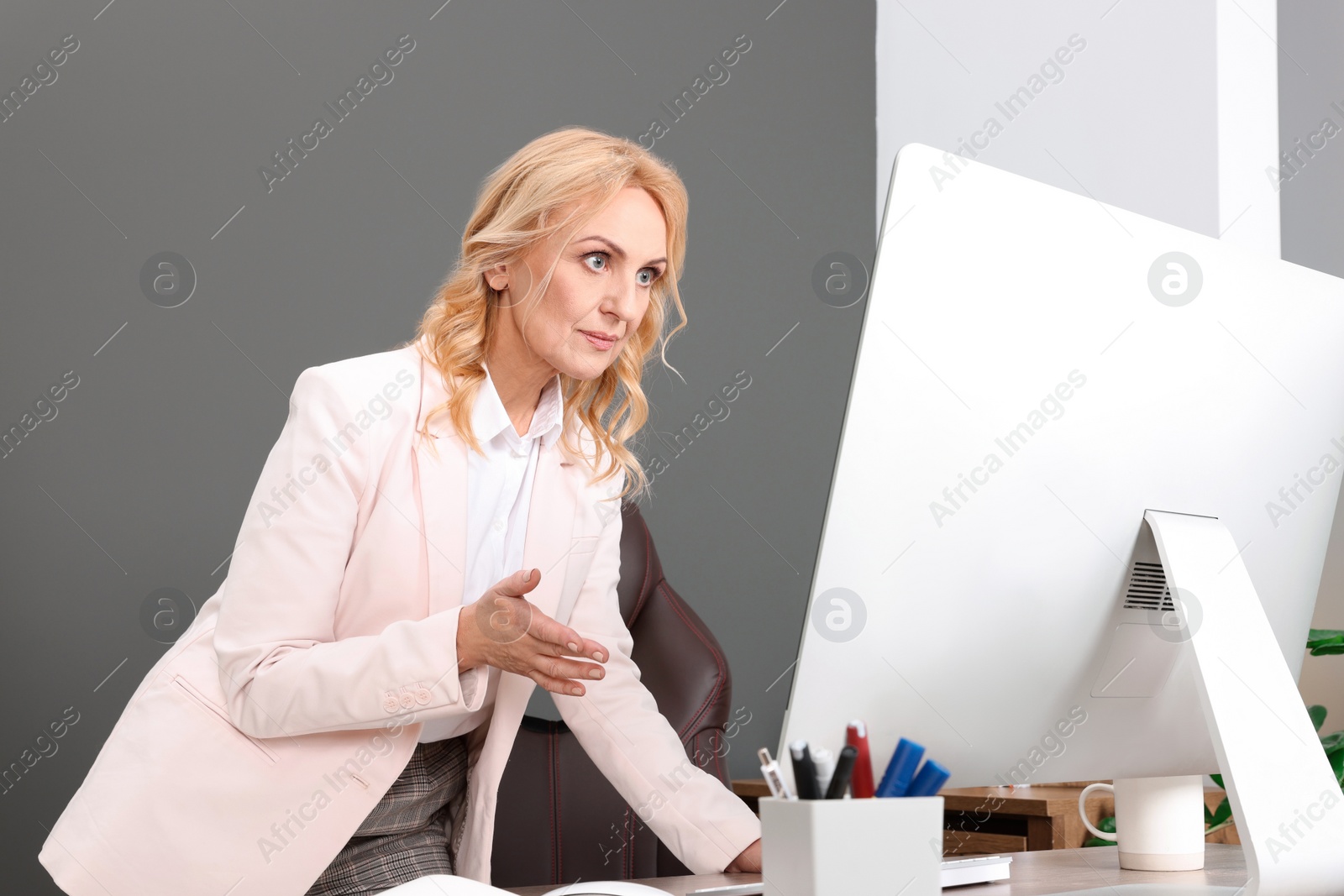 Photo of Happy lady boss working on computer in office. Successful businesswoman