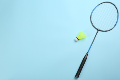 Photo of Racket and shuttlecock on light blue background, flat lay with space for text. Badminton equipment