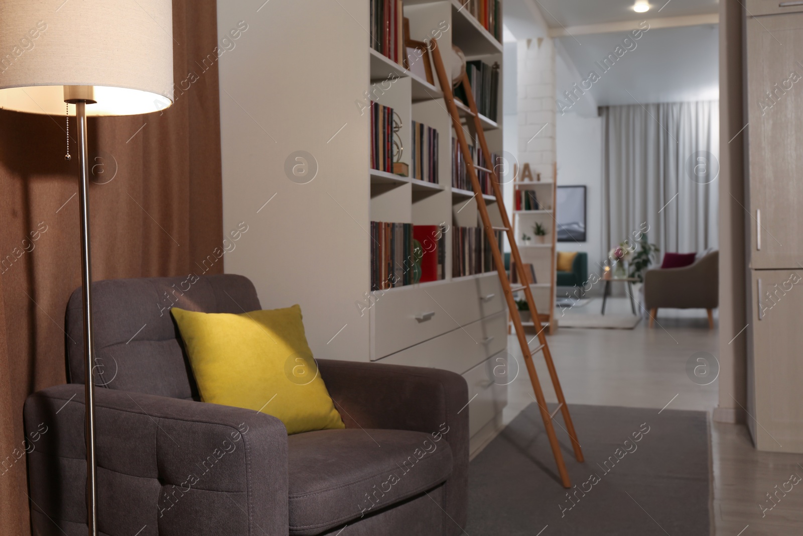 Photo of Cozy home library interior with collection of different books on shelves and comfortable place for reading