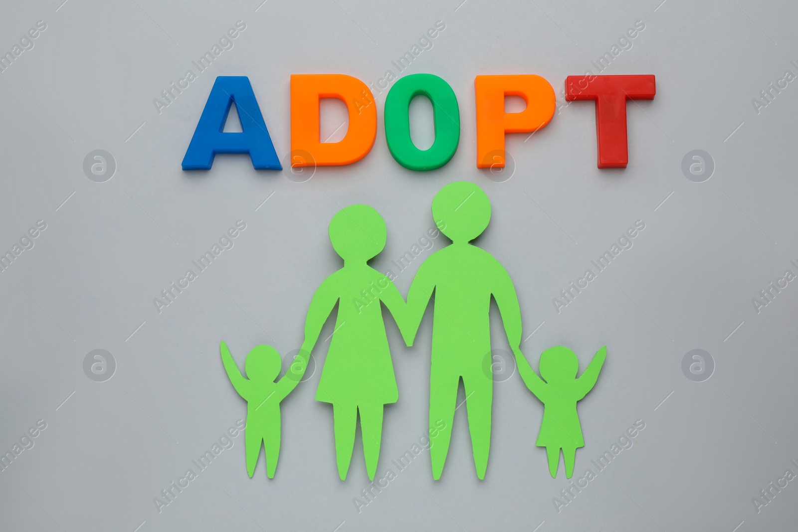 Photo of Family figure and word Adopt on grey background, flat lay