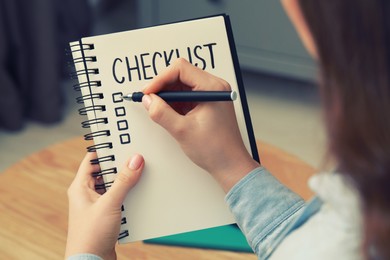 Woman filling Checklist with pen indoors, closeup