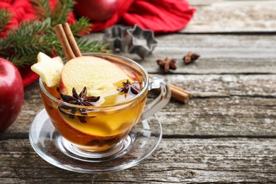 Photo of Hot mulled cider on wooden table. Space for text