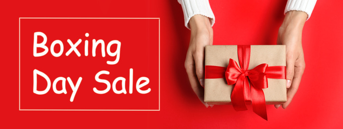 Image of Boxing day sale. Top view of woman with gift on red background, banner design