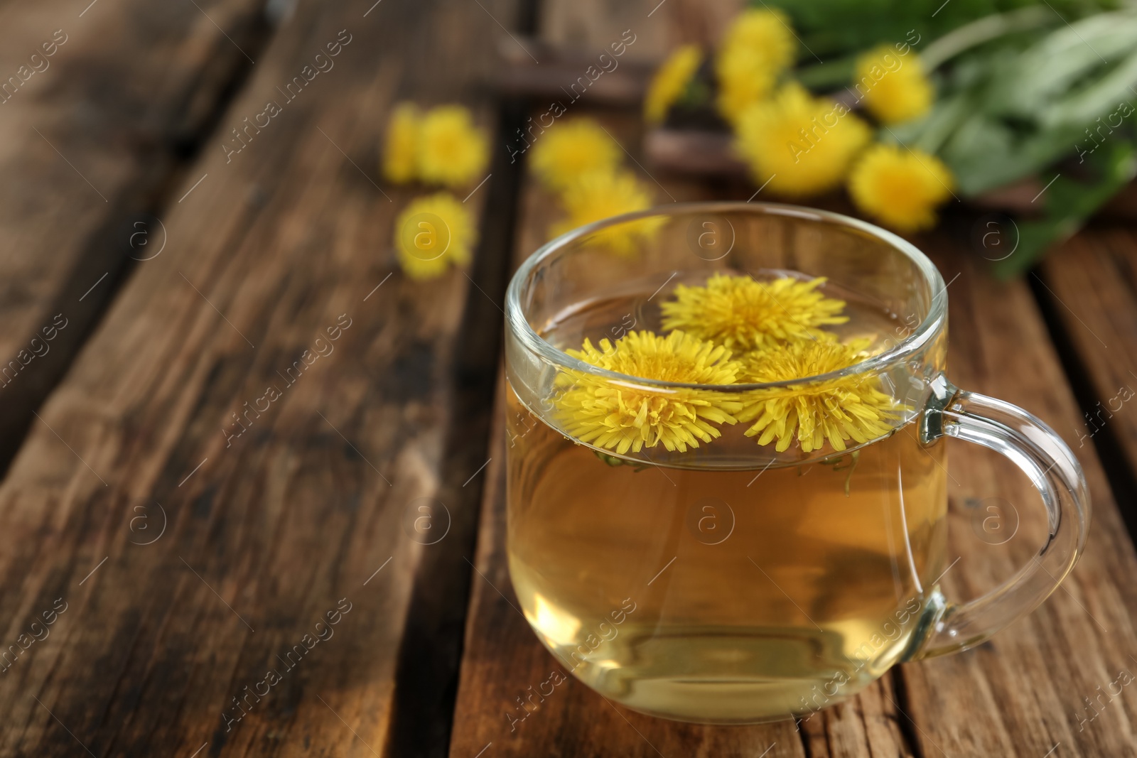 Photo of Delicious fresh dandelion tea on wooden table, closeup. Space for text