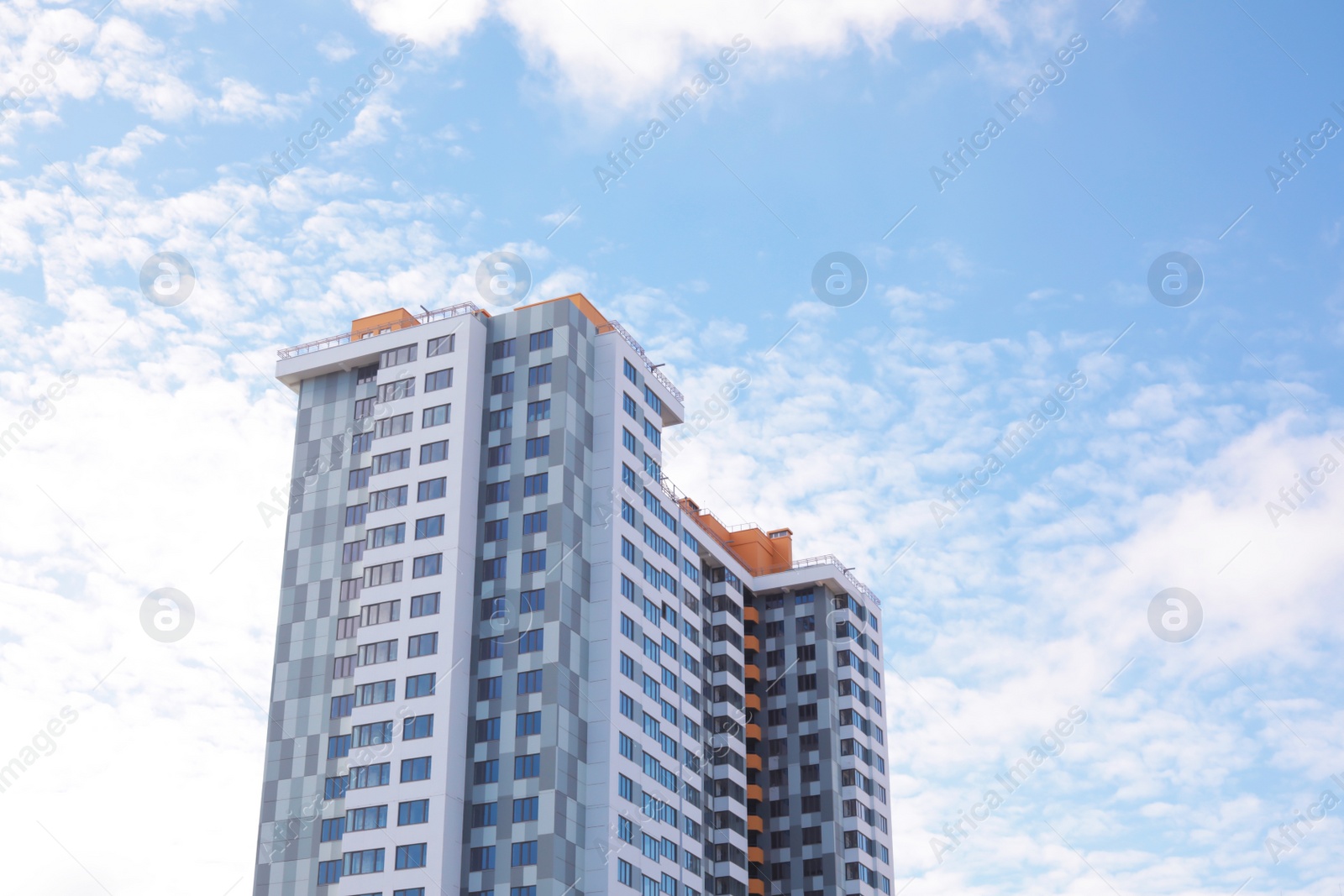 Photo of Building with tinted windows against cloudy sky. Modern architectural design