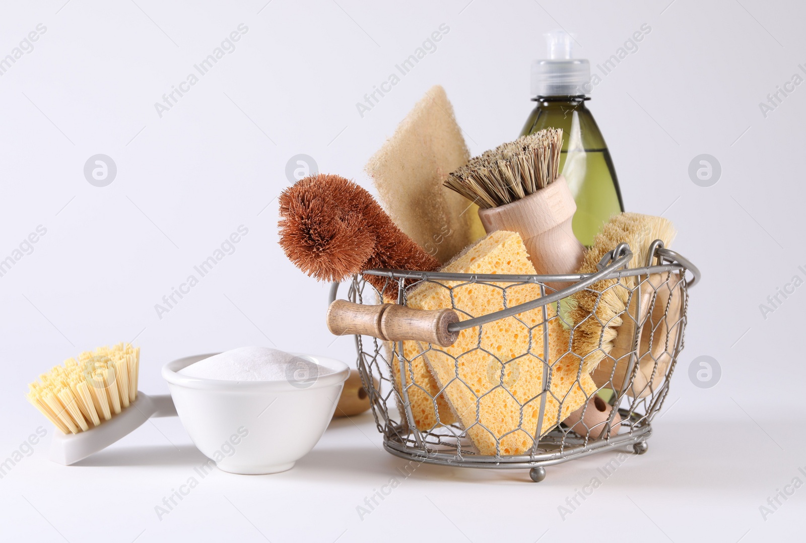 Photo of Set of different cleaning supplies in basket on white background